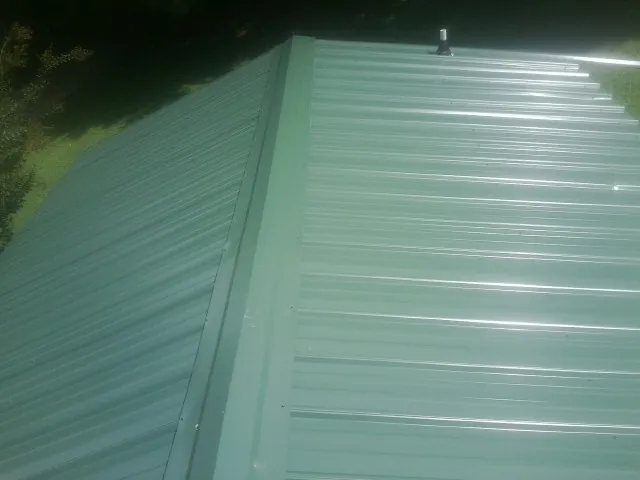 New green metal panels meeting at the ridge of a roof — Flat Roof Repair work by our crew in Granite Springs