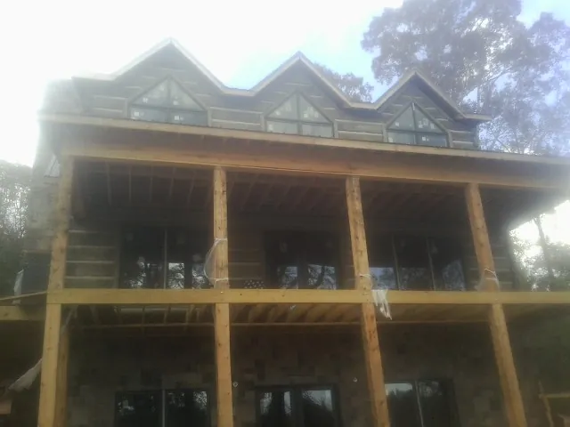 Dormers and porch framing on a large log home under construction — Roof Coating work by our crew in Granite Springs