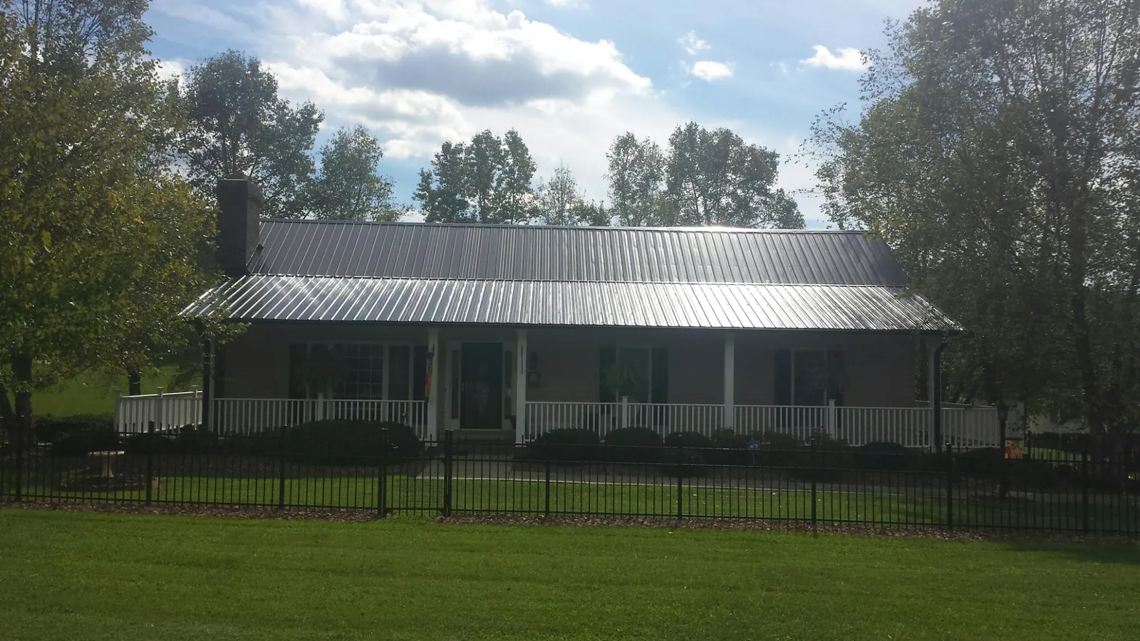Gray metal roof on a brick ranch with a full width front porch — Gutter Guard Installation work by our crew in Granite Springs