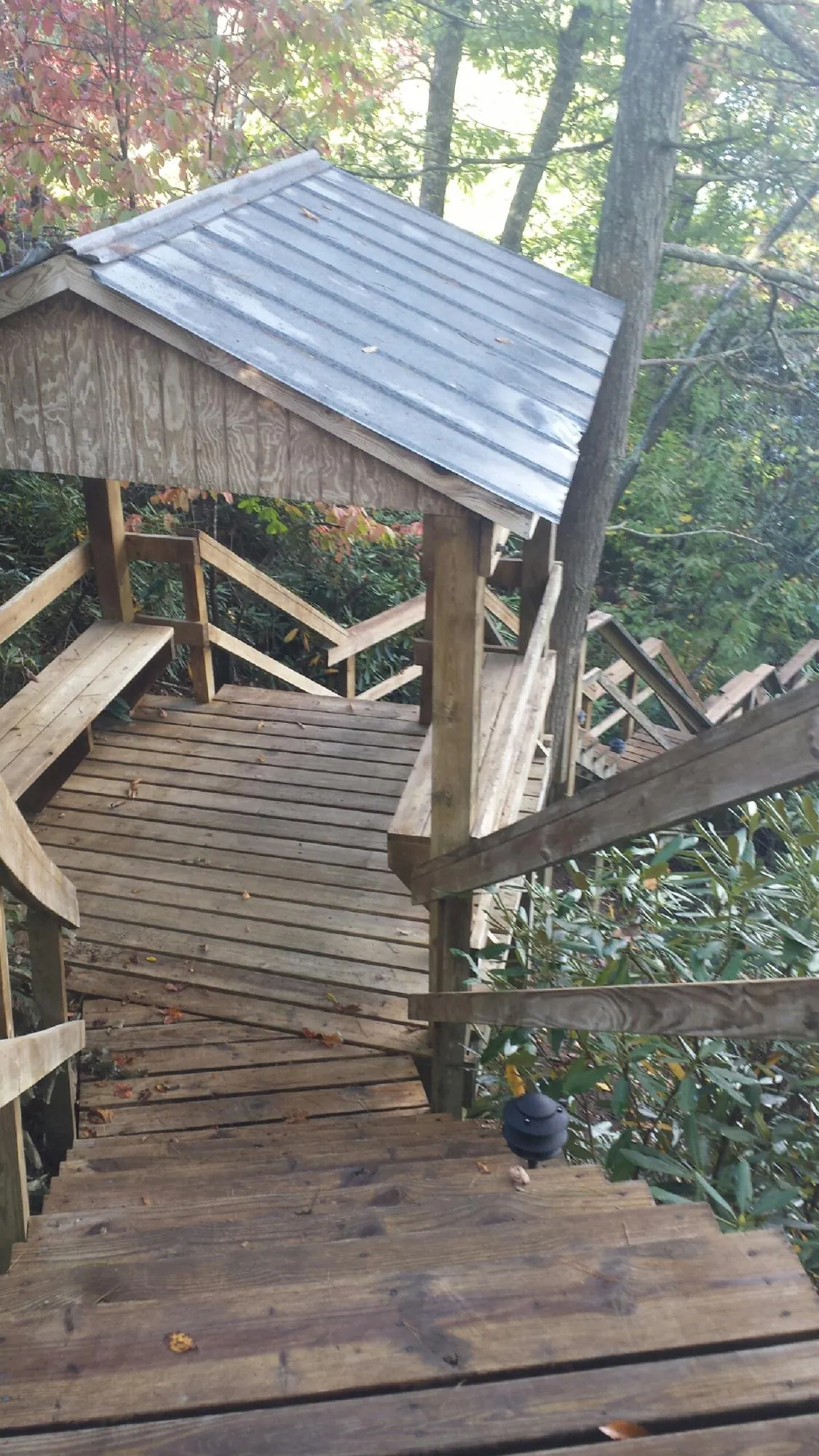 Metal roofed shelter over wooden steps on a wooded walkway — Skylight Repair & Installation work by our crew in Granite Springs