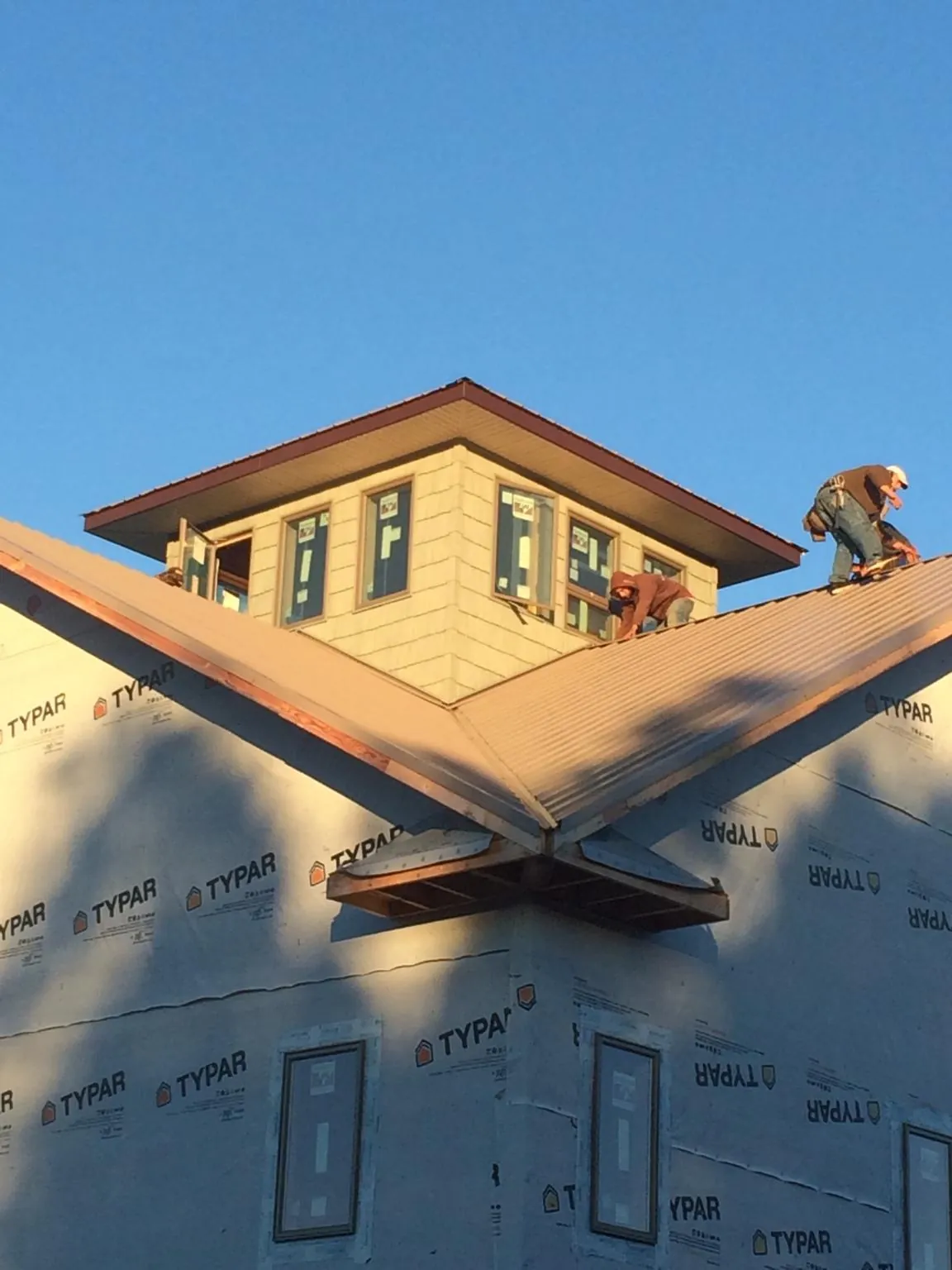 Roofers working around a rooftop cupola on a new metal roof at sunset — Roof Waterproofing in Granite Springs by Roofing Brothers